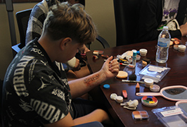  A student looks at a cut made from make up on his forearm.